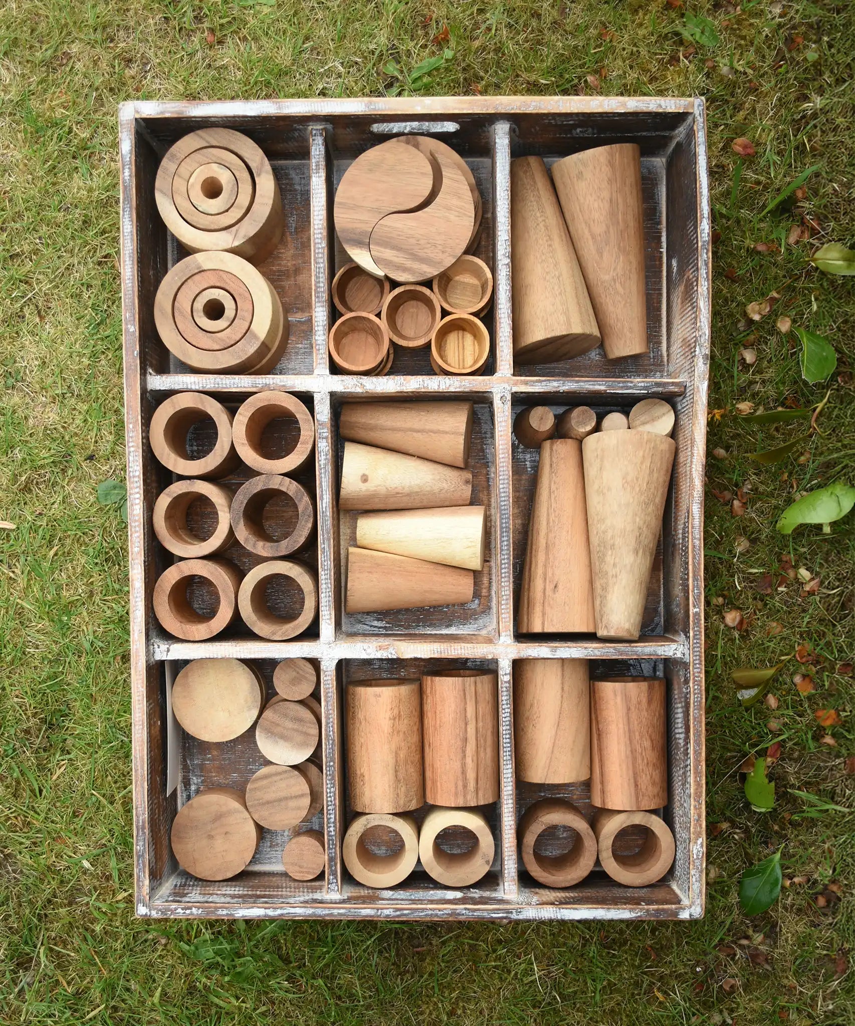 Papoose Toys wooden tinker tray school set placed on grass.