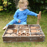 Child playing with the Papoose Toys wooden tinker tray school set outdoors.