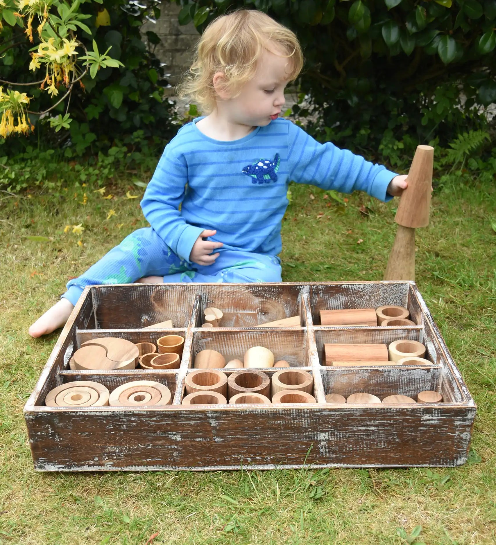 Child playing with the Papoose Toys wooden tinker tray school set outdoors.