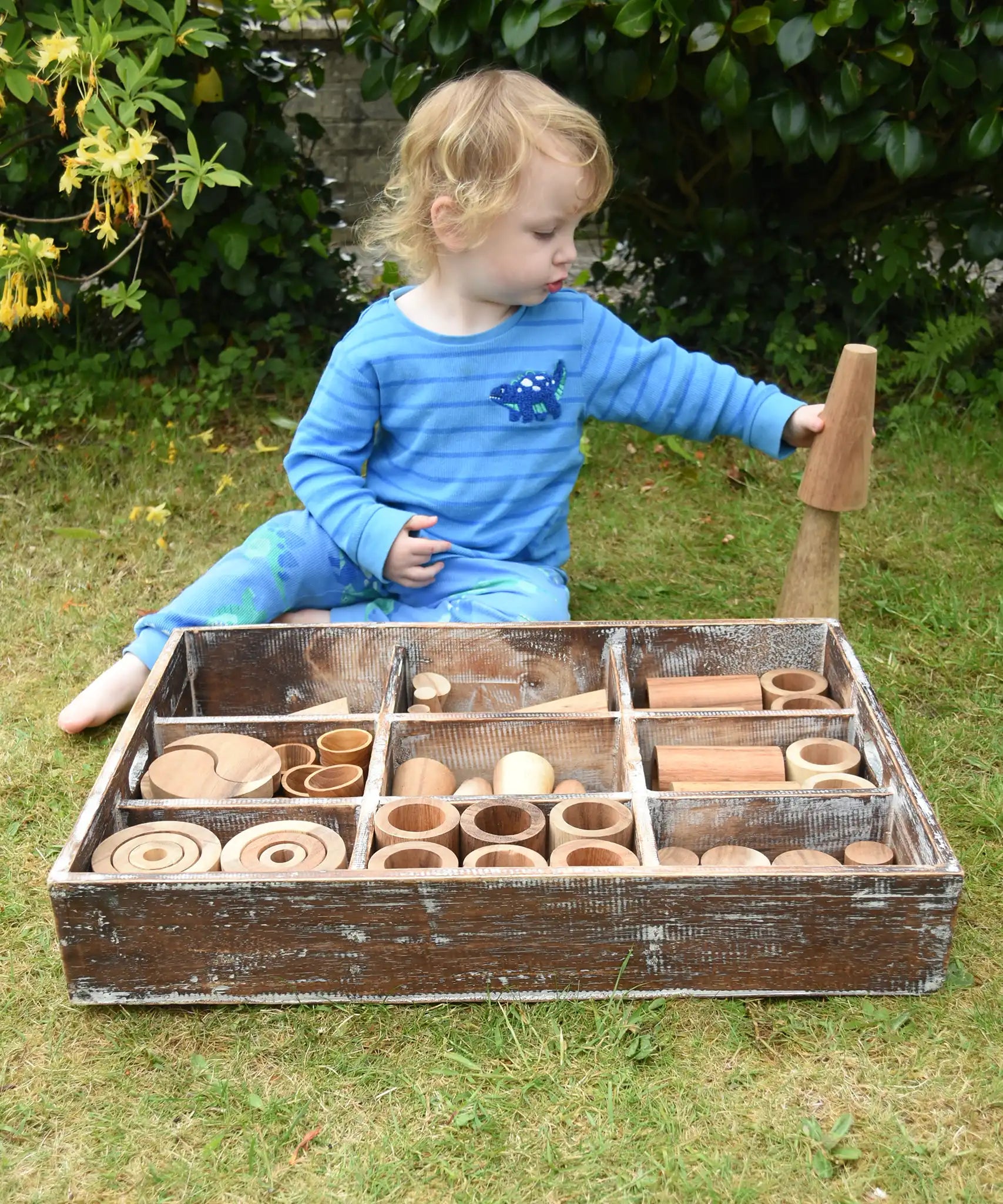 Child playing with the Papoose Toys wooden tinker tray school set outdoors.