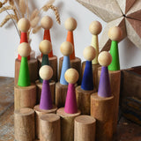 Papoose Toys wooden stacking trunks placed on a wooden desk with Goethe rainbow people placed on top.