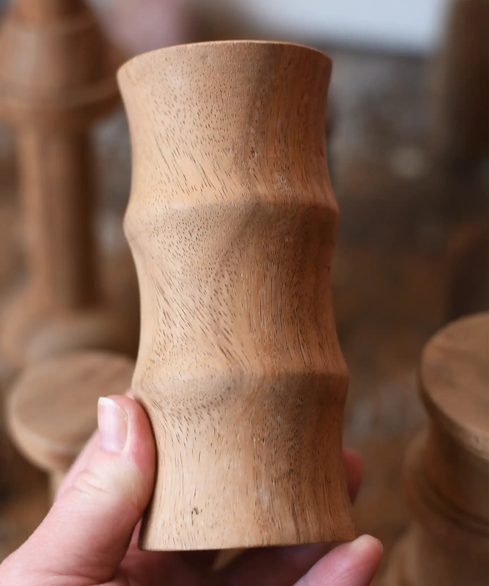 Large ridged spool from the Papoose Toys handmade wooden spool shape set in an adult's hand.