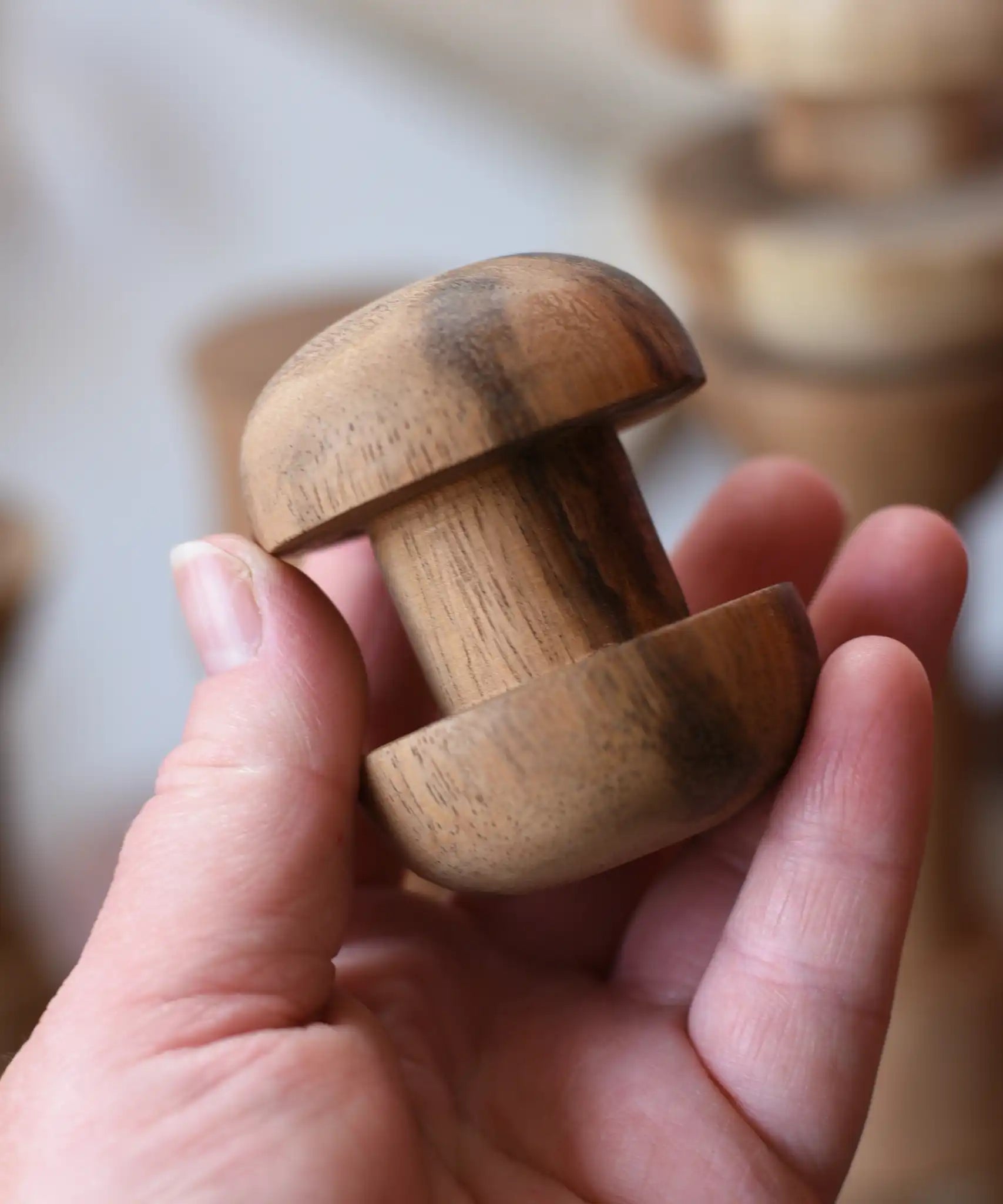 Round headed spool from the Papoose Toys handmade wooden spool shape set in an adult's hand.