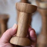 Spool from the Papoose Toys handmade wooden spool shape set in an adult's hand.