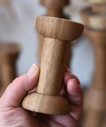 Spool from the Papoose Toys handmade wooden spool shape set in an adult's hand.