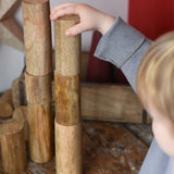 Papoose Toys wooden stacking trunks placed on a wooden desk. Child placing a trunk on top of a stack.
