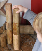 Papoose Toys wooden stacking trunks placed on a wooden desk. Child placing a trunk on top of a stack.