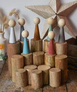 Papoose Toys wooden stacking trunks placed on a wooden desk with earth people peg dolls placed on top.