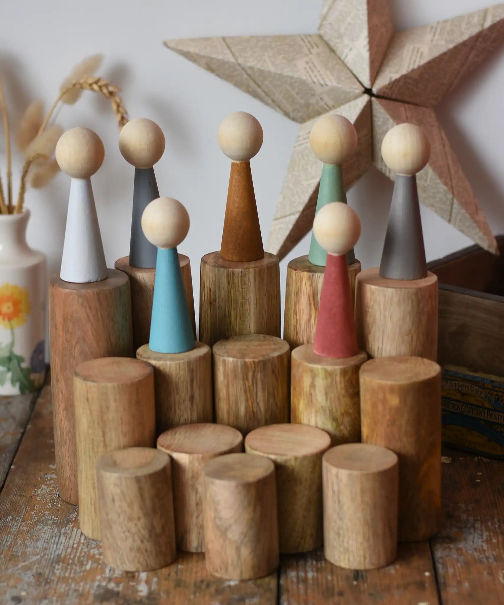 Papoose Toys wooden stacking trunks placed on a wooden desk with earth people peg dolls placed on top.