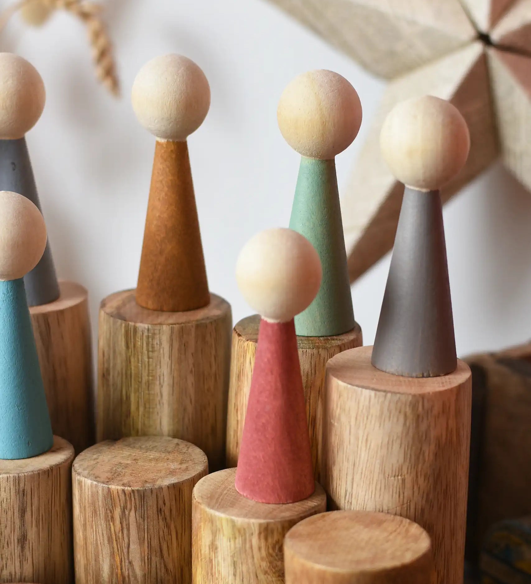 Papoose Toys wooden stacking trunks with earth people wooden peg dolls placed on top.