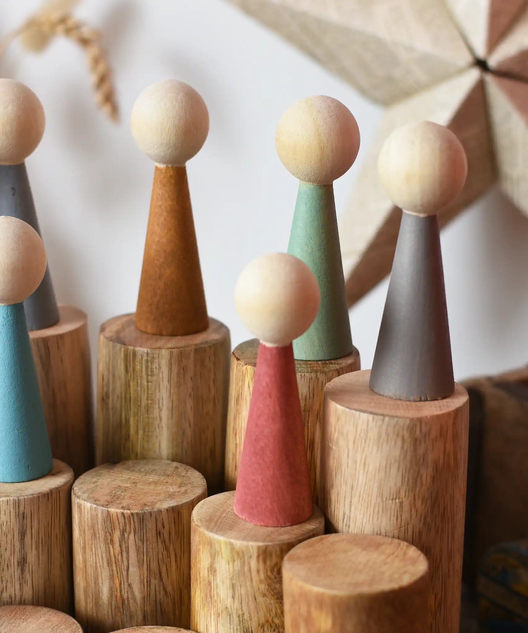 Papoose Toys wooden stacking trunks with earth people wooden peg dolls placed on top.