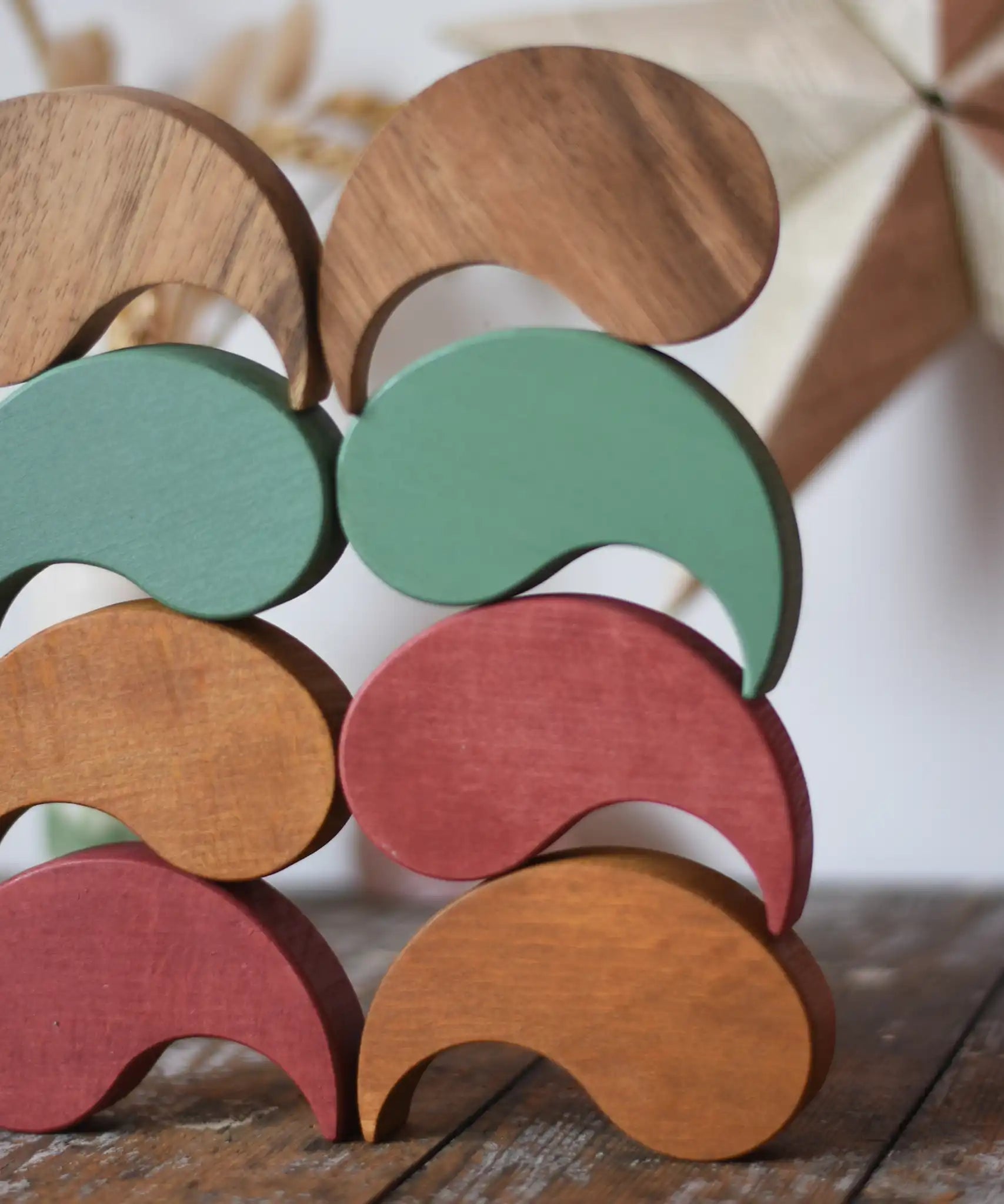 Papoose Toys wooden earth and natural yim yams stacked on a wooden desk.