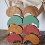 Papoose Toys wooden earth and natural yim yams  stacked up on a wooden desk.