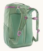 The back of the Patagonia refugito 18 litres daypack in ellwood green. showing the pastel green padded shoulder pads with pink detail and mesh side pockets on 100% recycled material 