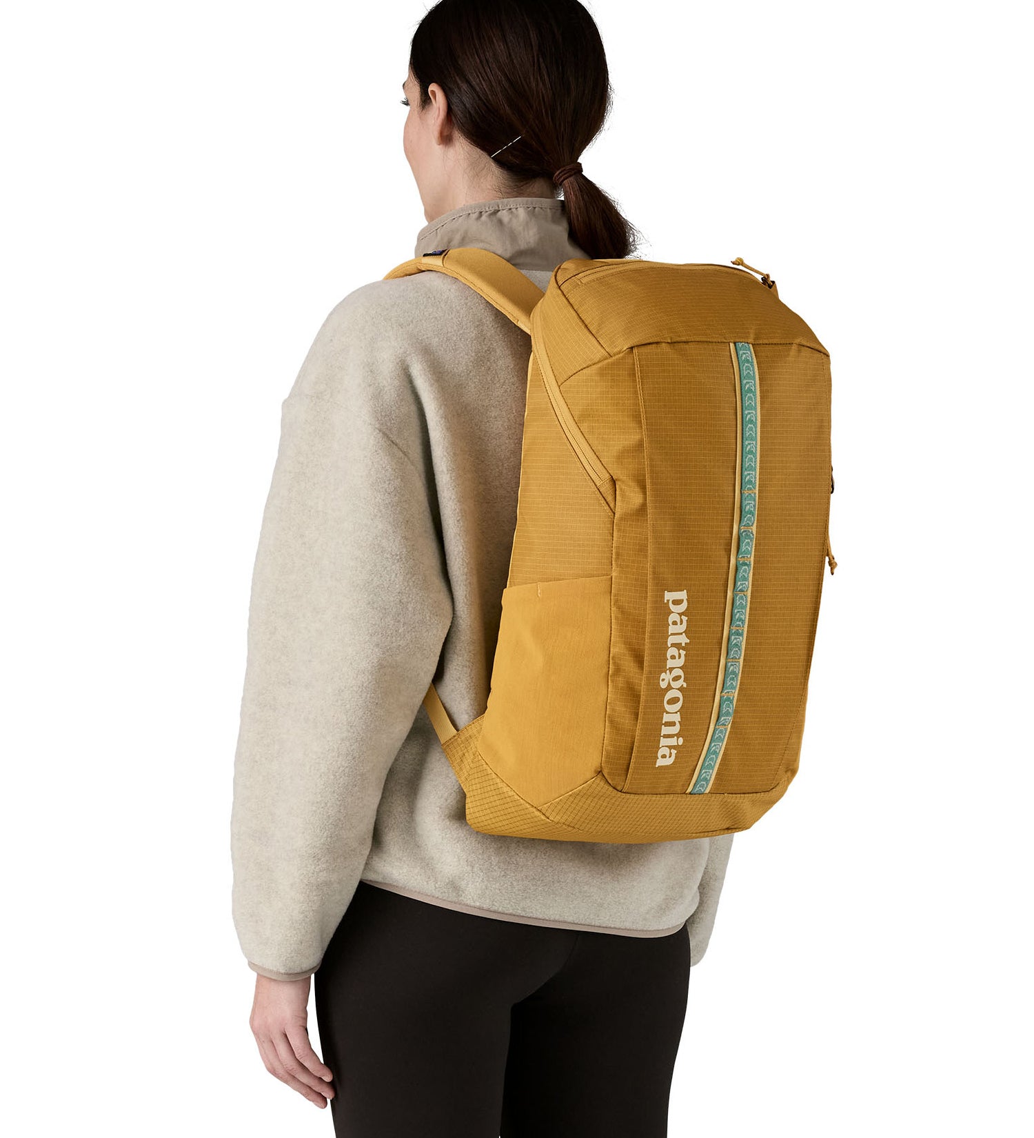 The back of a woman wearing The Patagonia Black Hole Pack 32 litre capacity backpack in a Beeswax Tan golden yellow colour