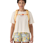 Patagonia 30L yellow refugio day backpack with a flower design  worn by an adult shoulder strap and clip detail