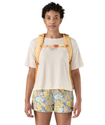 Patagonia 30L yellow refugio day backpack with a flower design  worn by an adult shoulder strap and clip detail