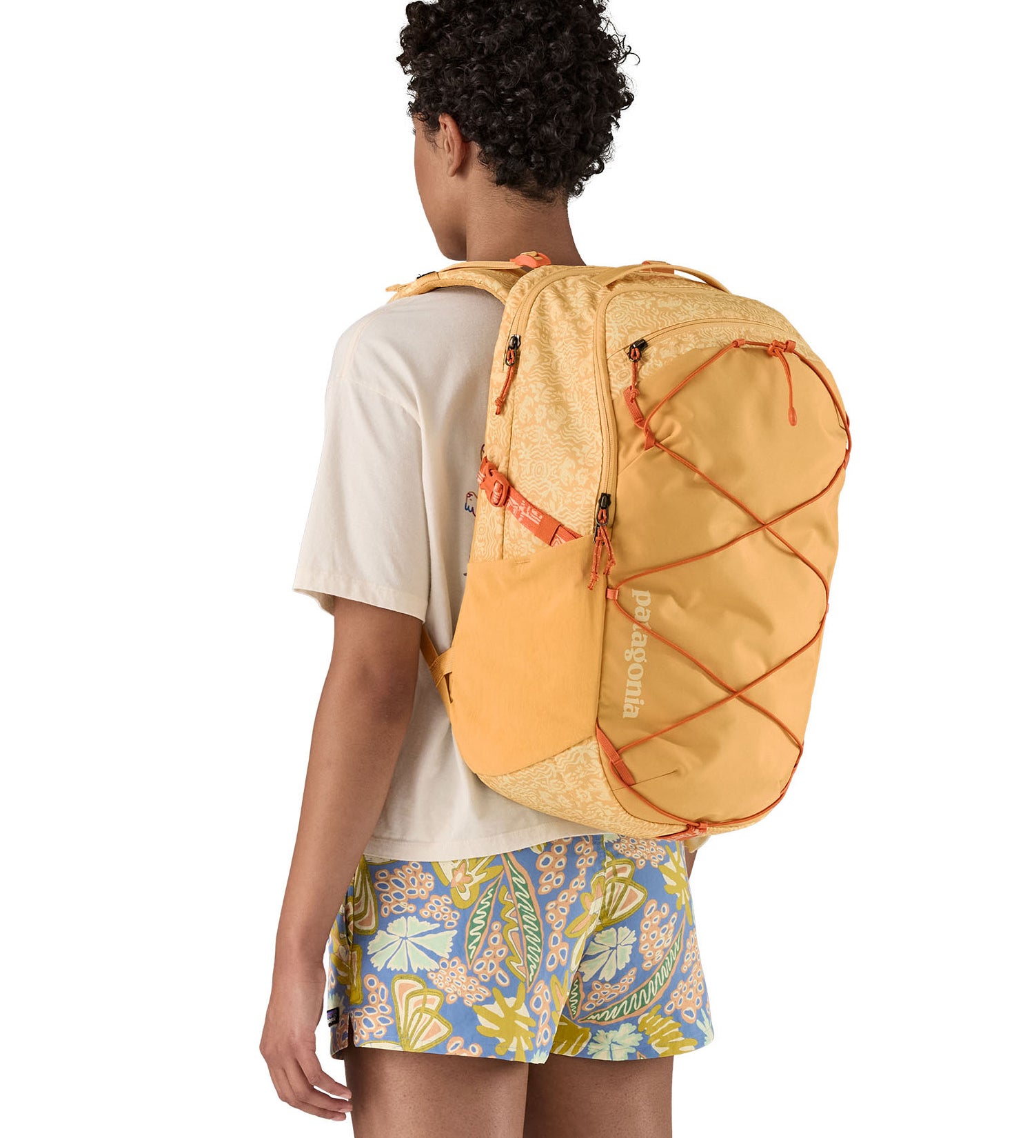 Patagonia 30L yellow refugio day backpack with a flower design  worn by an adult