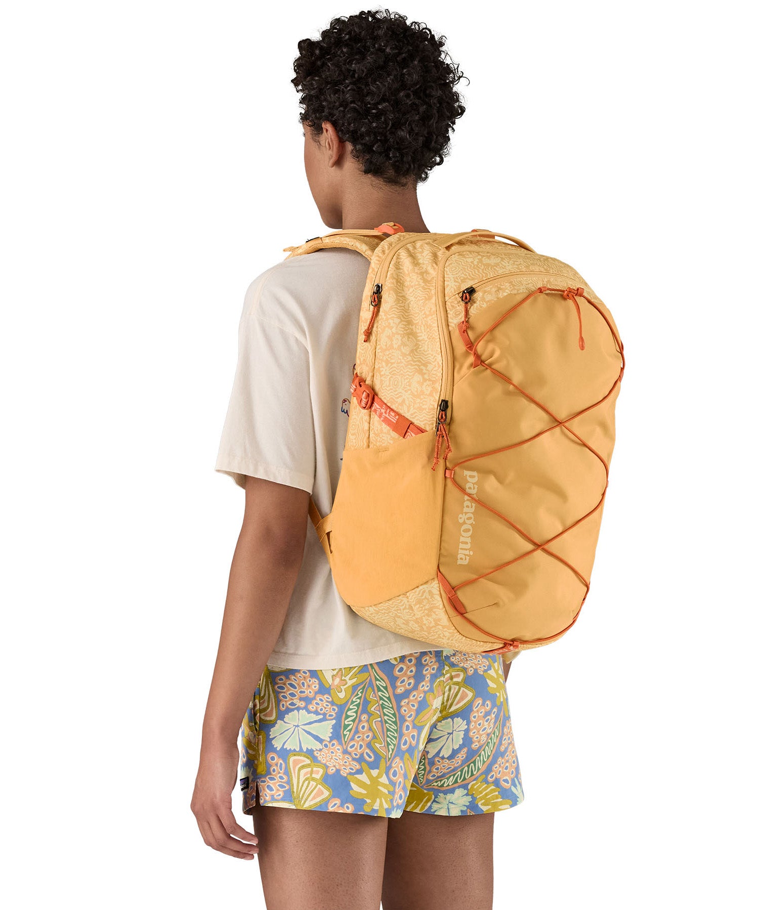 Patagonia 30L yellow refugio day backpack with a flower design  worn by an adult