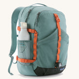 Patagonia 30L refugio backpack in blue sage with white bottle in the side holder and orange gear loops and quick release buckles.