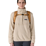 Front view of a woman wearing the Patagonia 32L black hole talon gold backpack showing the chest strap and buckle detail for a secure fit. 