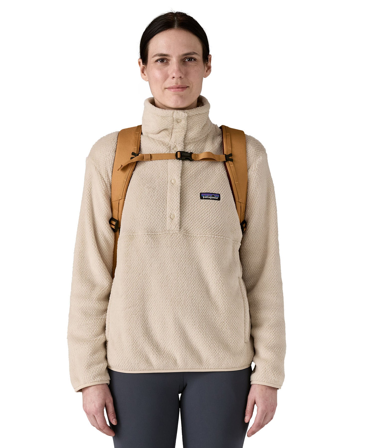 Front view of a woman wearing the Patagonia 32L black hole talon gold backpack showing the chest strap and buckle detail for a secure fit. 