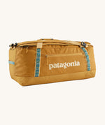Patagonia 70 litres duffel bag in a gold colour on a cream background.