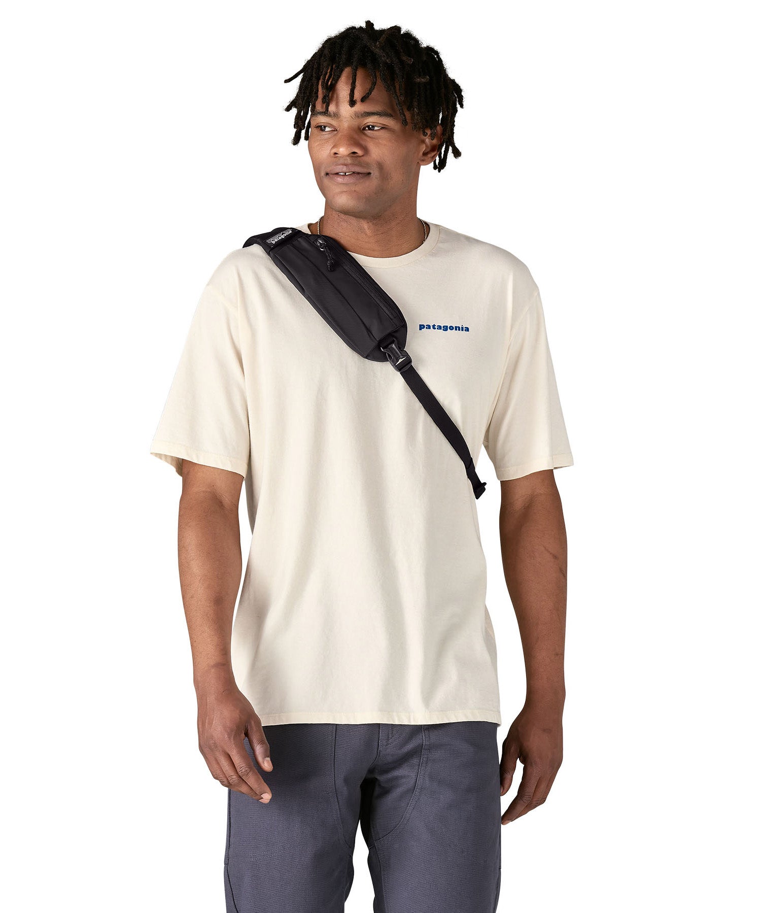 Patagonia 8L atom sling bag in a black colour worn by an adult shoulder strap detail