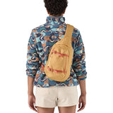 Patagonia 8L atom sling bag in a yellow colour worn by an adult