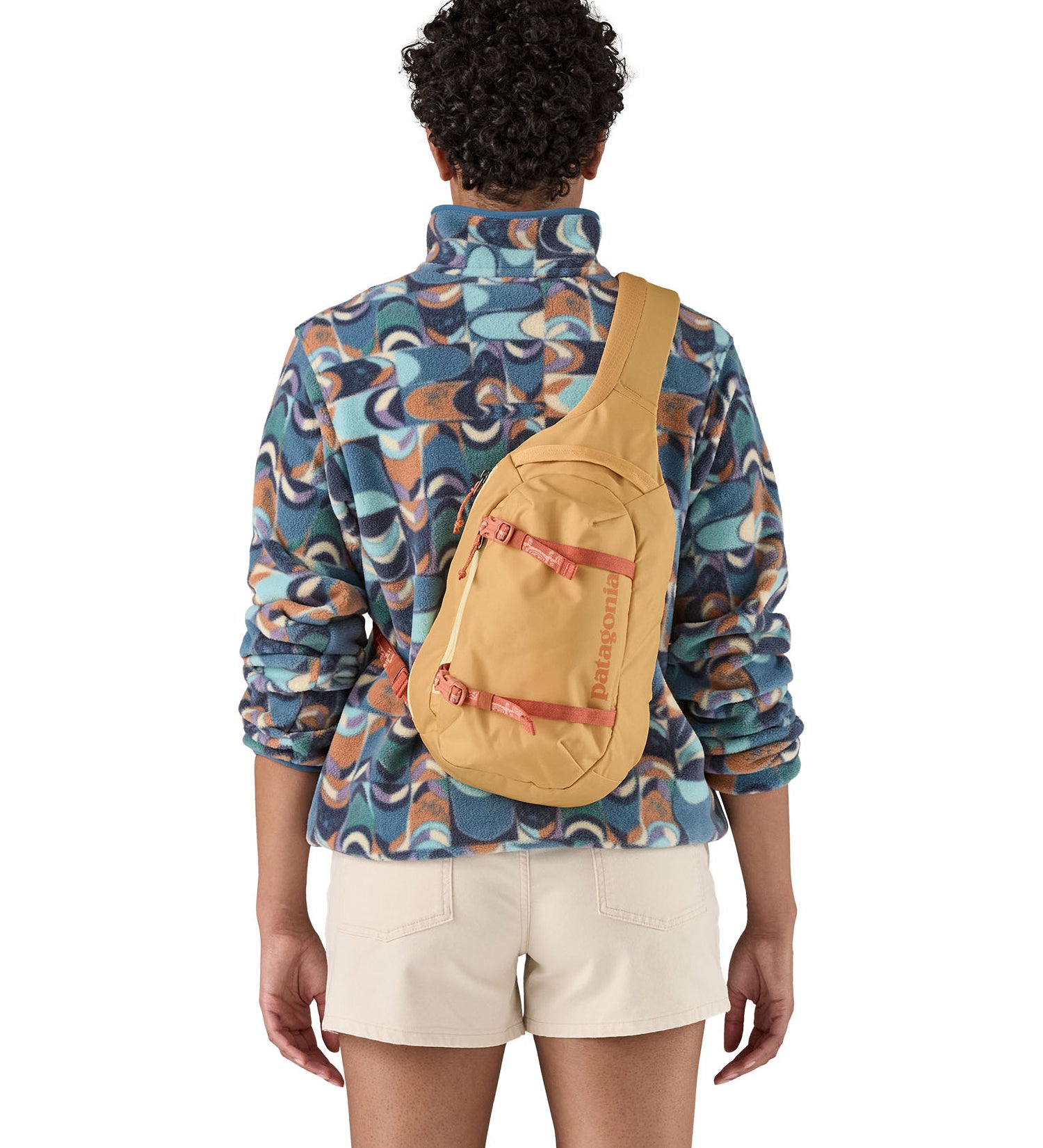 Patagonia 8L atom sling bag in a yellow colour worn by an adult