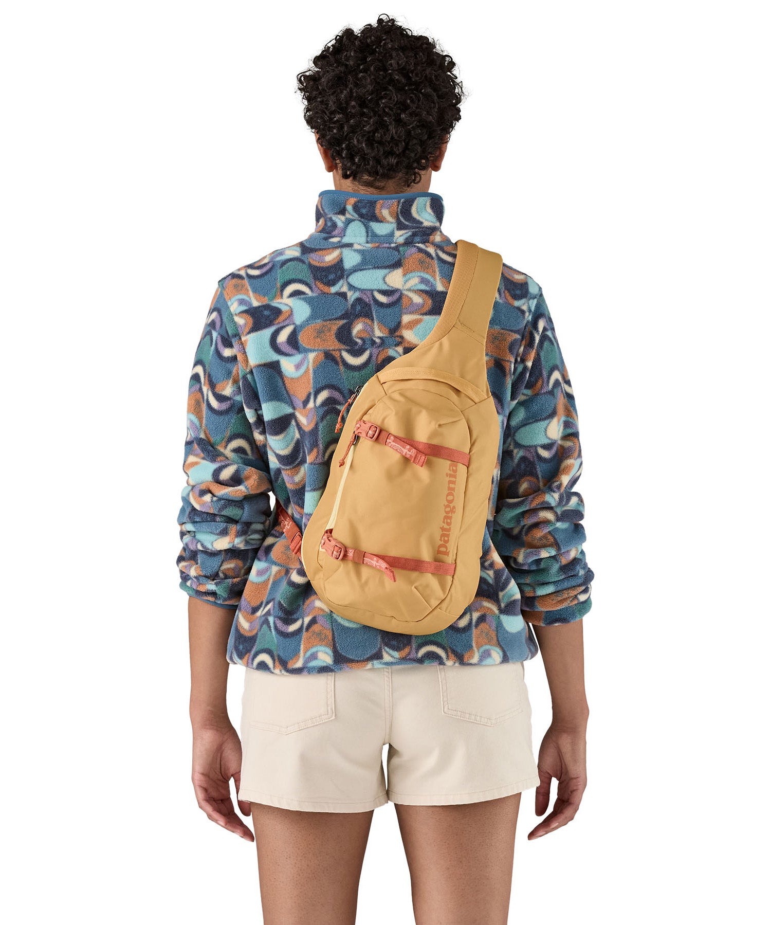 Patagonia 8L atom sling bag in a yellow colour worn by an adult