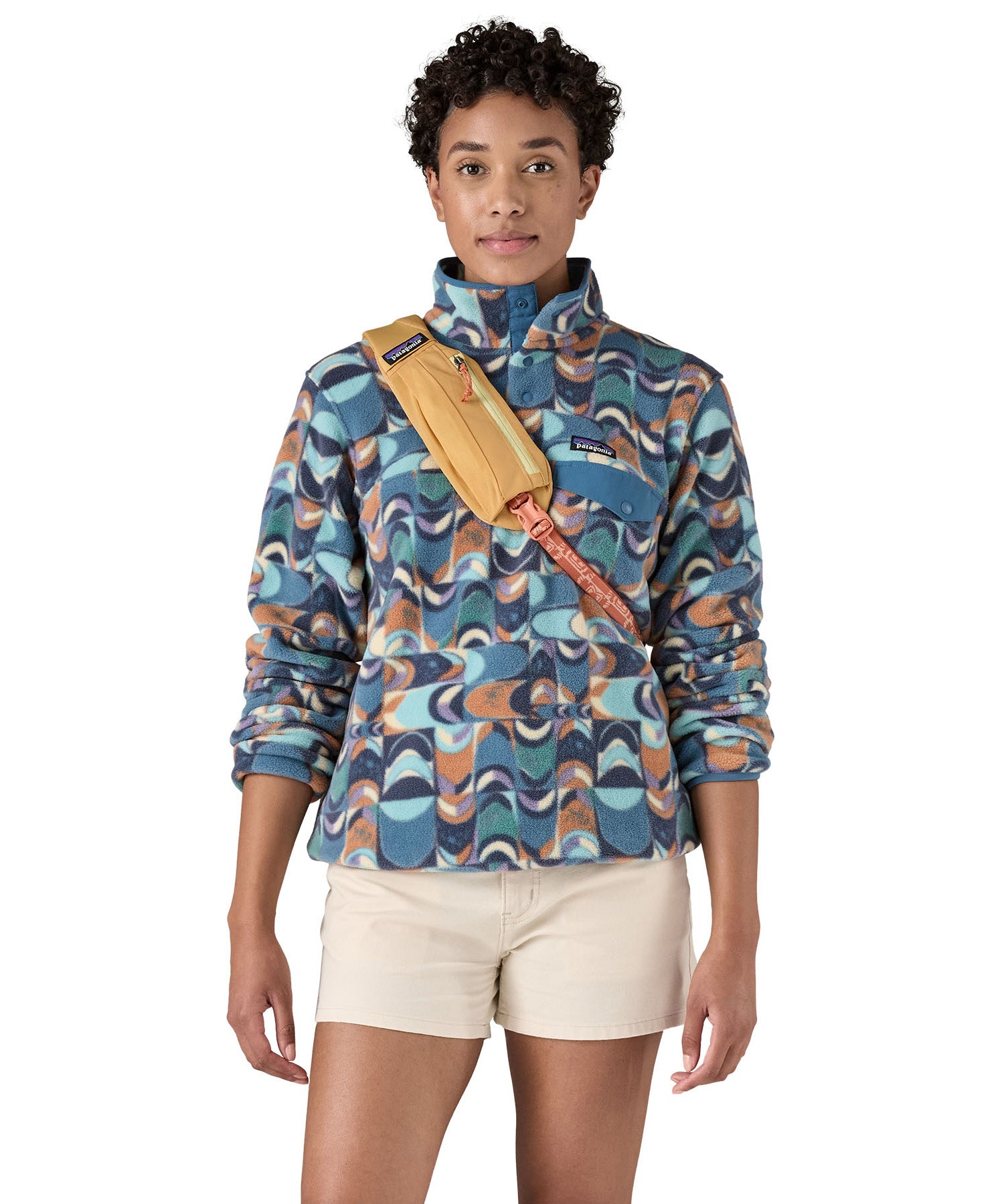 Patagonia 8L atom sling bag in a yellow colour worn by an adult shoulder strap detail