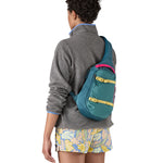 Patagonia 8L atom sling bag in a turquoise colour worn by an adult