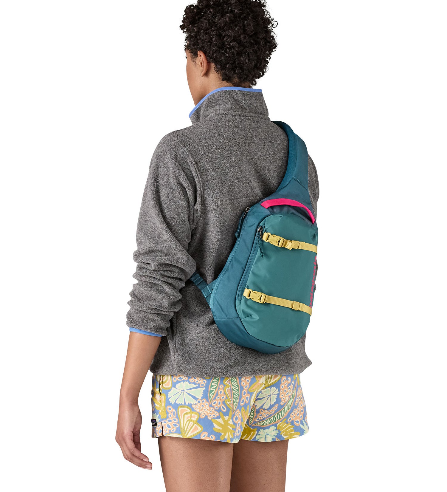 Patagonia 8L atom sling bag in a turquoise colour worn by an adult