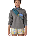 Patagonia 8L atom sling bag in a turquoise colour worn by an adult shoulder strap detail