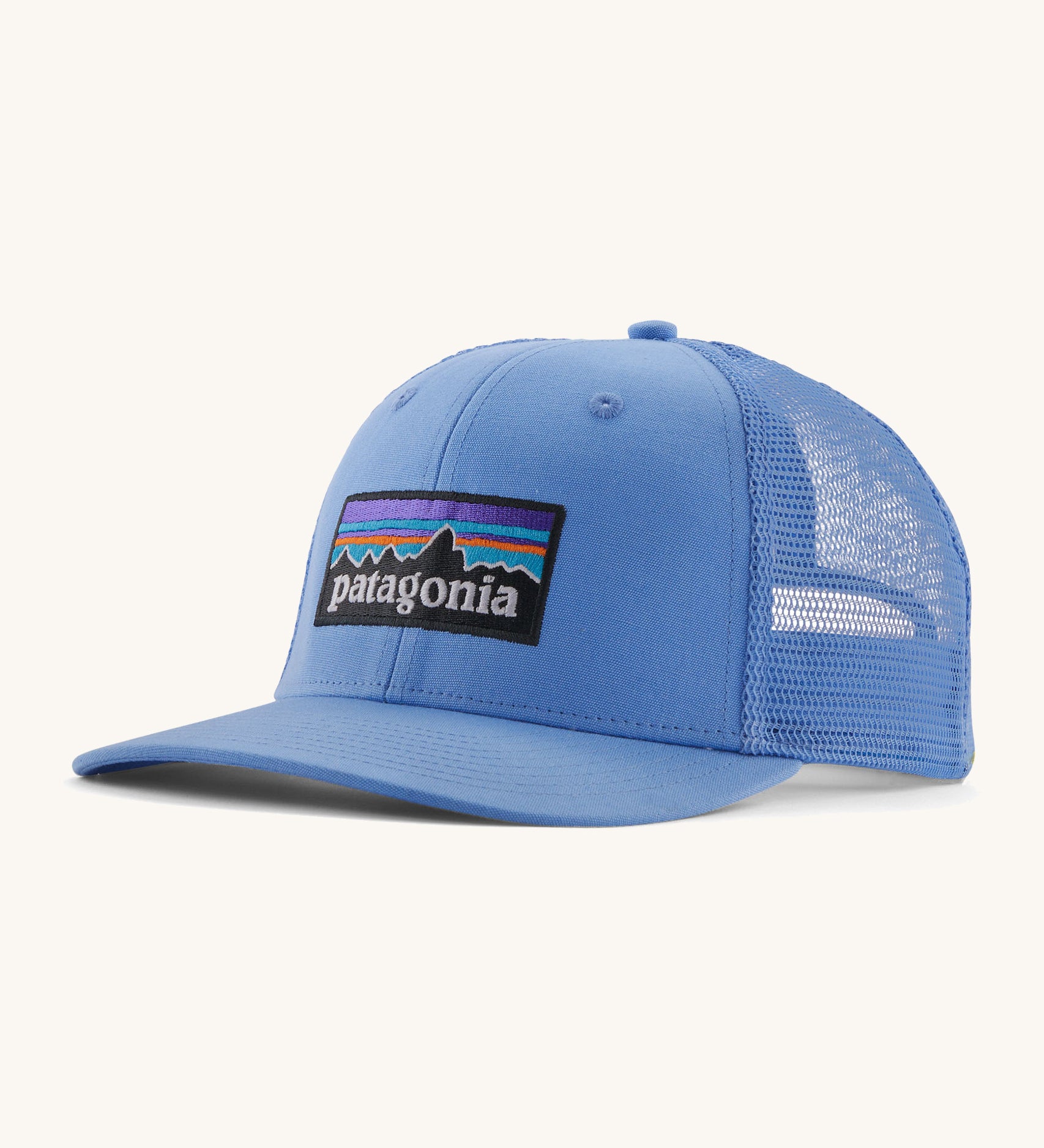 Patagonia adult trucker hat in blue on a cream background.