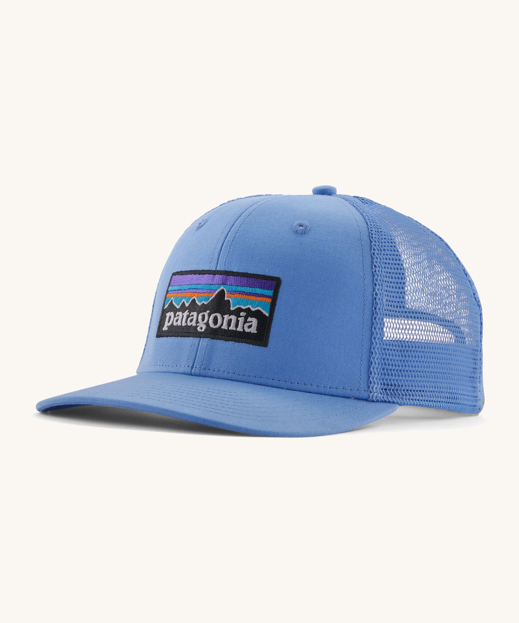Patagonia adult trucker hat in blue on a cream background.