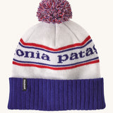 Patagonia adult beanie in white with a blue turn up ribbed brim. Features a red white and blue pom pom on top and the logo branding knitted into the hat. 
