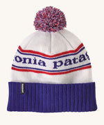 Patagonia adult beanie in white with a blue turn up ribbed brim. Features a red white and blue pom pom on top and the logo branding knitted into the hat. 