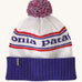Patagonia adult beanie in white with a blue turn up ribbed brim. Features a red white and blue pom pom on top and the logo branding knitted into the hat. 