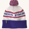 Patagonia adult beanie in white with a blue turn up ribbed brim. Features a red white and blue pom pom on top and the logo branding knitted into the hat. 