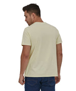 A man wearing a Patagonia Adult Fitz Roy Icon Responsibili-Tee in a Birch White colour stood in front of a plain background. The man is facing away from the camera showing the back of the t-shirt which is plain. 