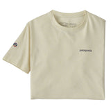 The Patagonia Adult Fitz Roy Icon Responsibili-Tee in a Birch White colour folded into a square with one sleeve out. The grey coloured patagonia logo can be seen on the top right of the top. A small round mountain badge detail can be seen on the left sleeve.