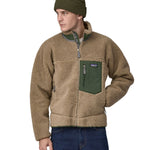 A man wearing a Patagonia Men's Classic Retro-X Jacket in a Seabird Grey colour and a green beanie hat.