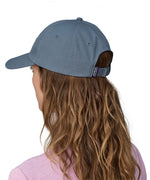 A woman wearing a Patagonia Adult P-6 Label Trad Cap in a mid utility blue colour. The woman is facing away from the camera showing the back of the cap.