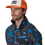 A man wearing a Patagonia Adult P-6 Logo Trucker Hat White Redtail Rust