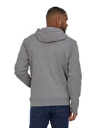 A man wearing a Patagonia Adult P-6 Logo Uprisal Hoody in a Gravel Heather grey colour stood in front of a plain background. He is facing away from the camera showing the back of the hoody. 