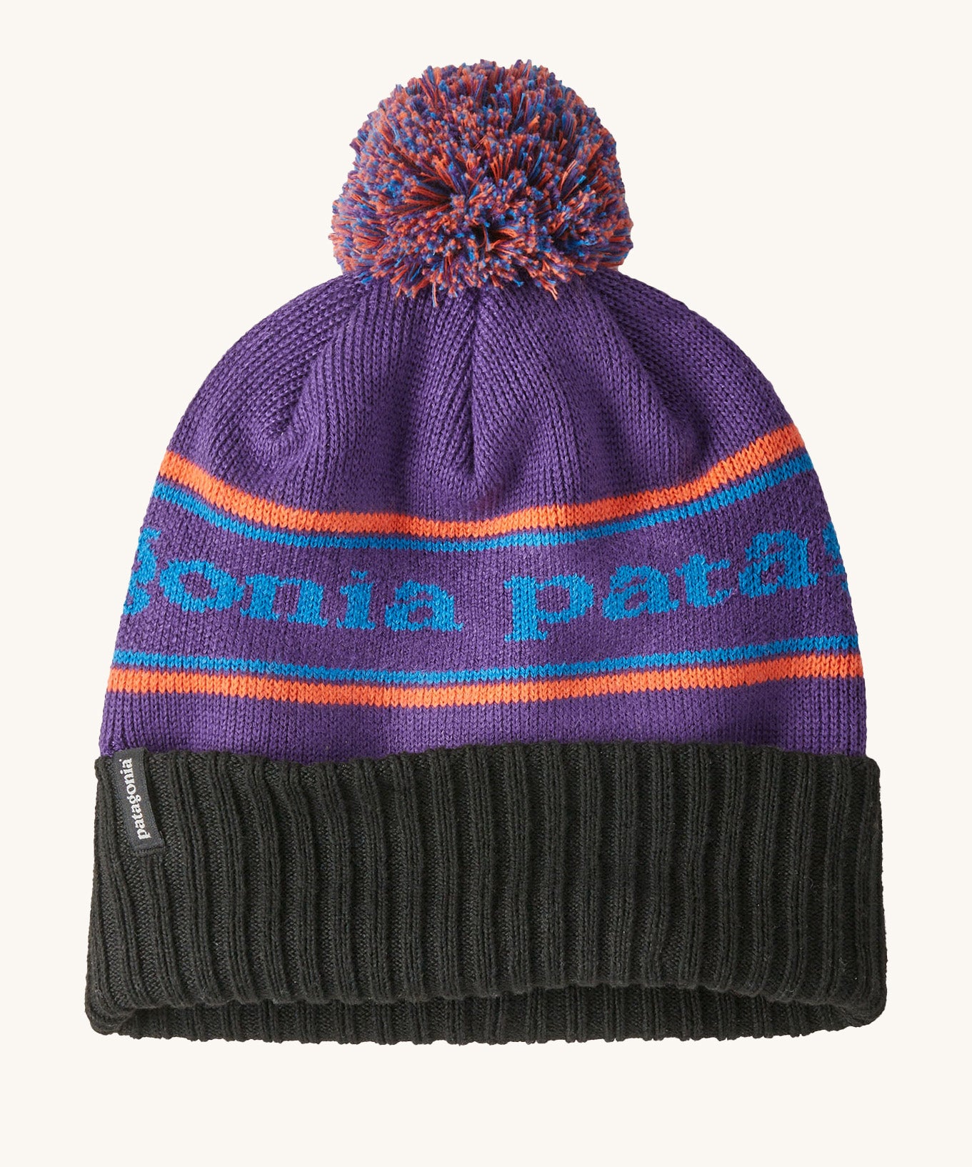 A black and purple adult Patagonia beanie hat with a orange strip and light blue branding on a cream background