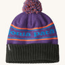 A black and purple adult Patagonia beanie hat with a orange strip and light blue branding on a cream background