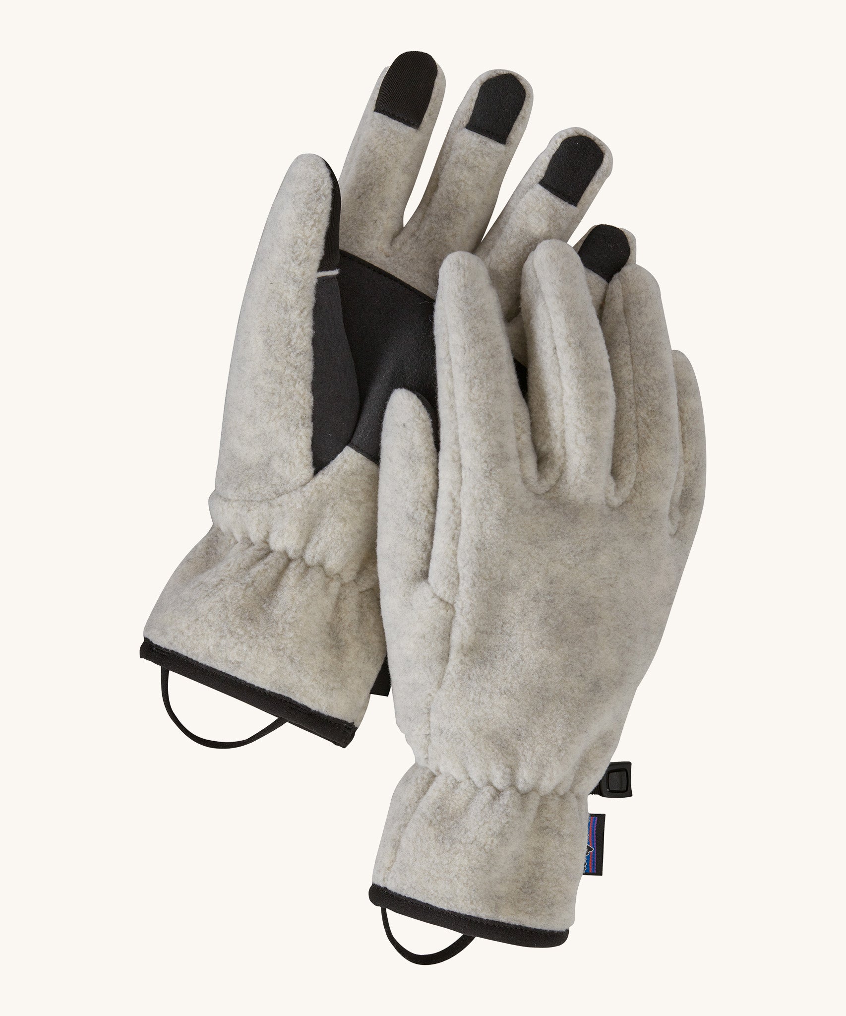 Alternative view of the Patagonia adult synchilla gloves in oatmeal heather. Features a grip on the palms and fingertips. Logo label is stitched on the side with a clip on each glove for easy carrying